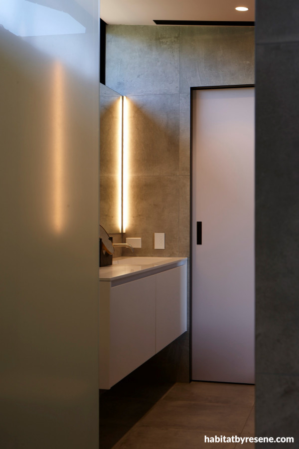 In the powder room, Resene Blanched Pink on the door and ceiling complements the grey tiling and Resene Black trims and door jambs.  